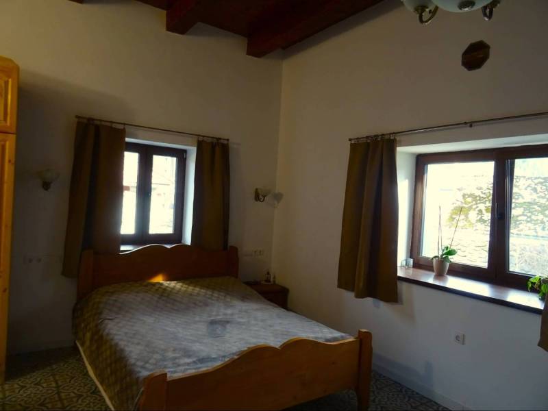 A bedroom in a family house with a wooden bed, a window, and curtains.