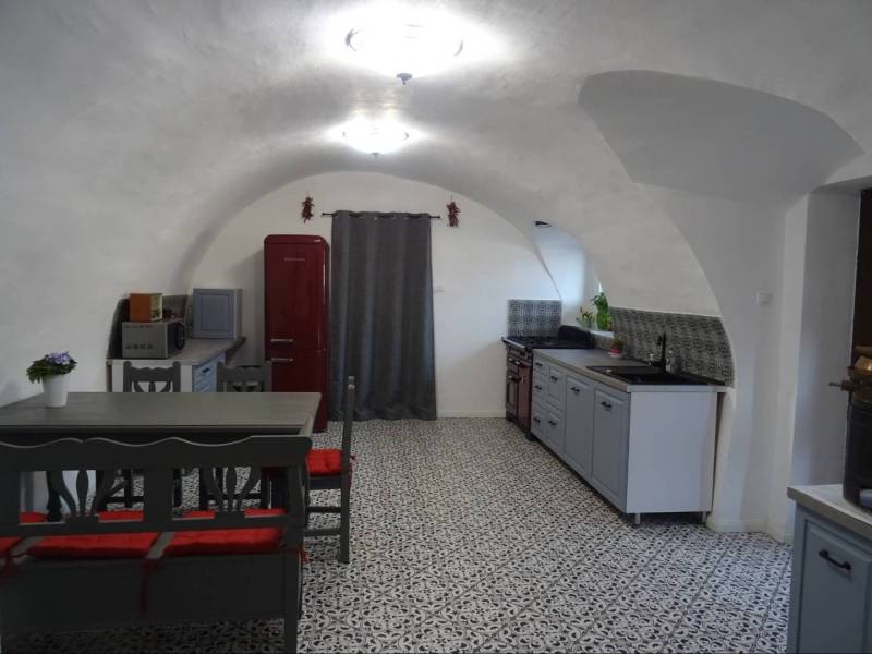 A kitchen in a family house with a vaulted ceiling, a red refrigerator, and patterned flooring.