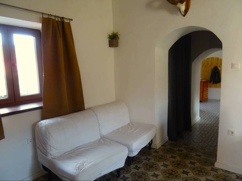 A family house with a white sofa, decorated floor, and arched passage.