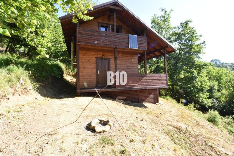 A wooden cabin in nature near Bytča, surrounded by trees and a fire pit.