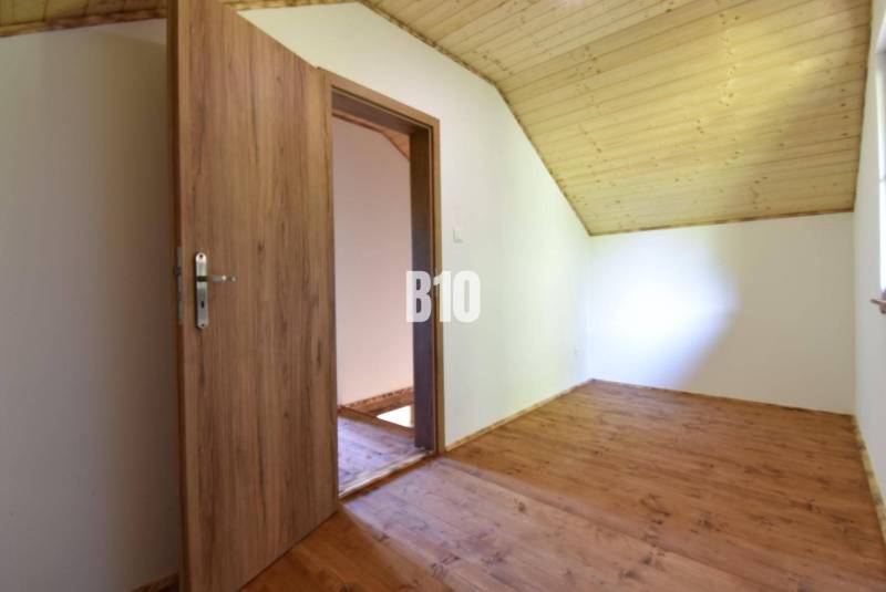 A room in a cottage with wooden doors and a wooden floor.