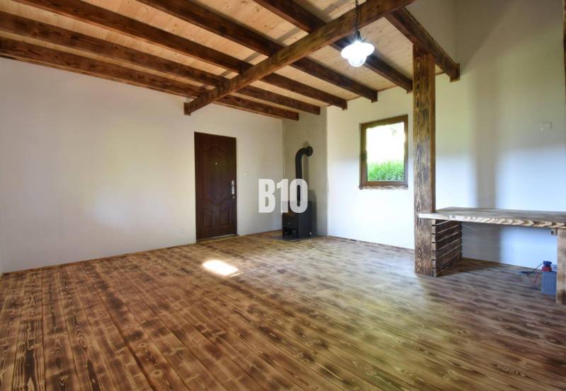 Interior of a cabin with a wooden ceiling, floor, and stove.
