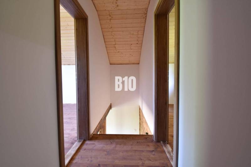A wooden attic with a hallway in the cottage, with a natural ceiling and floor.
