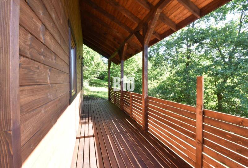A wooden terrace of a cottage in Bytča surrounded by greenery and forest scenery.