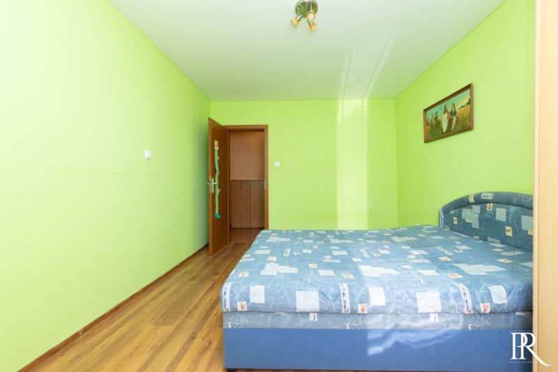 Bedroom in a 2-room apartment with a bed and light green walls.