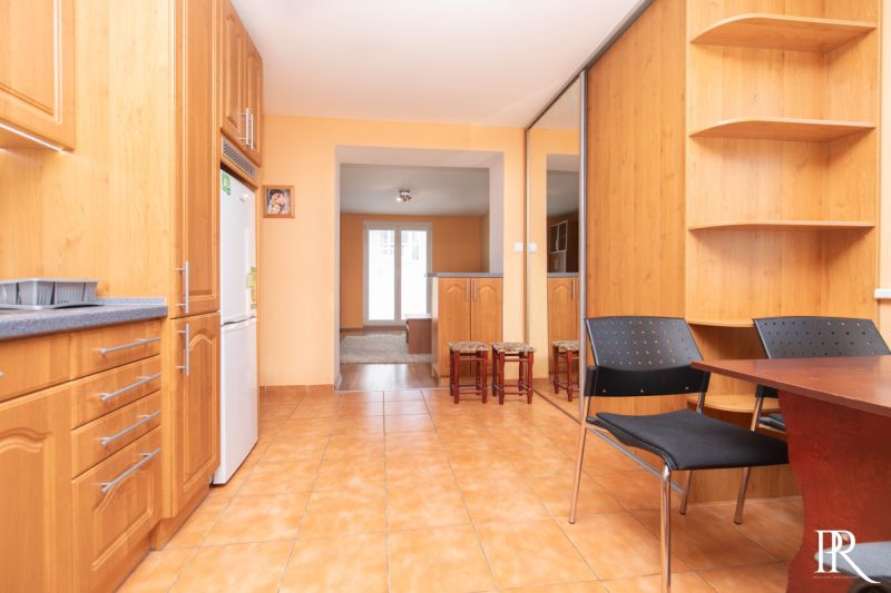 A kitchen and dining room in a 2-room apartment with wooden furniture and ceramic tiles.