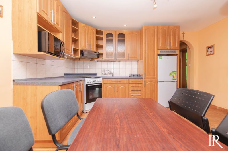 A kitchen in a 2-room apartment with a wooden kitchen unit and a dining table.