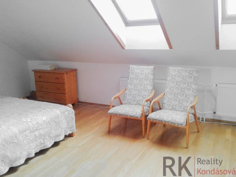 An attic room with two armchairs, a dresser, and a bed in a two-room apartment.