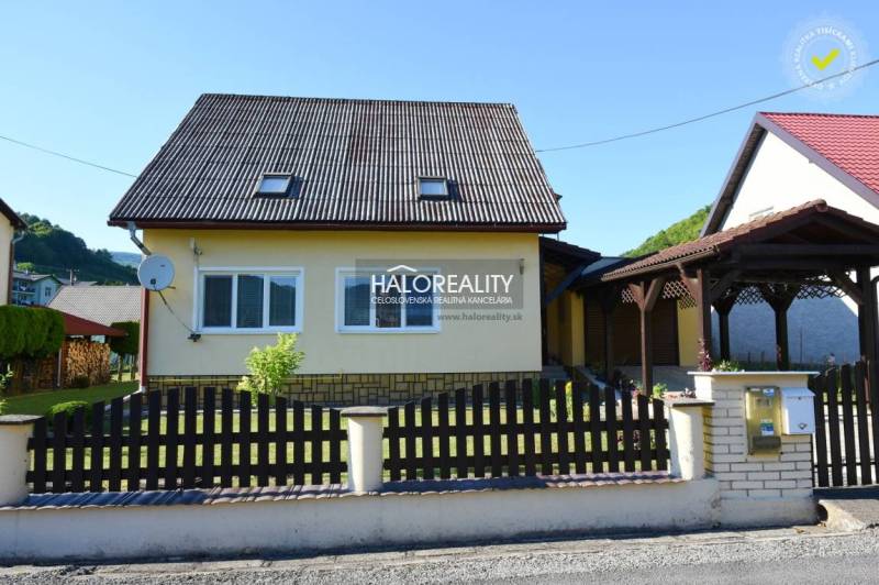 A family house in Župkov with a wooden fence and a satellite dish on a sunny plot.