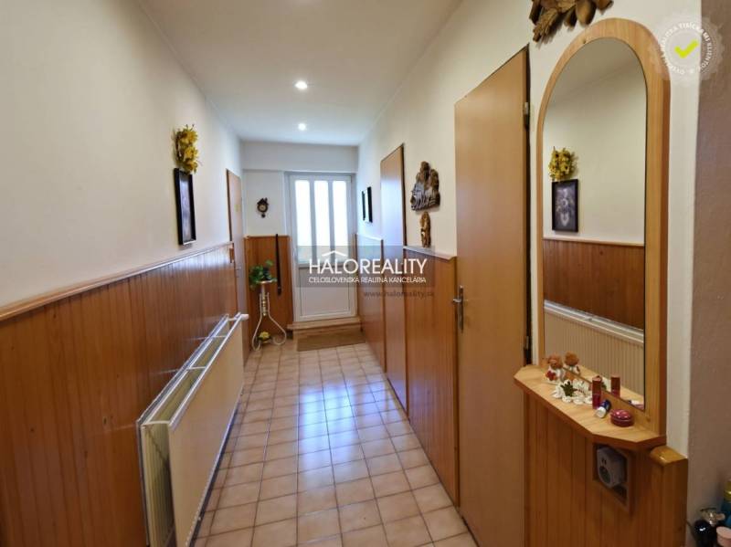 A hallway in a family house with wooden paneling, decorative elements, and an entrance door.