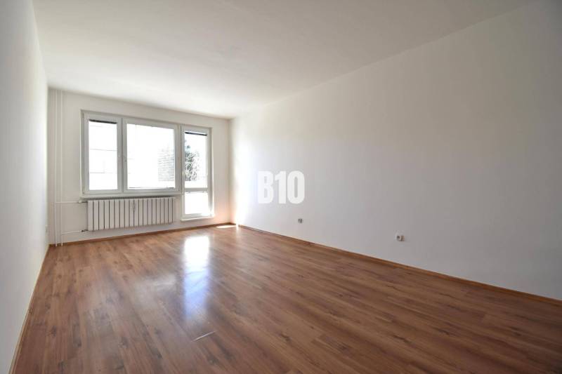 A room in a 4-room apartment with a wooden floor and a large window.