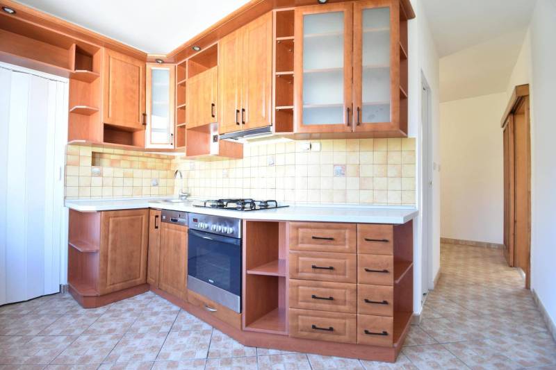 A kitchen with built-in cabinets and an oven in a 4-room apartment, tiles and light walls.