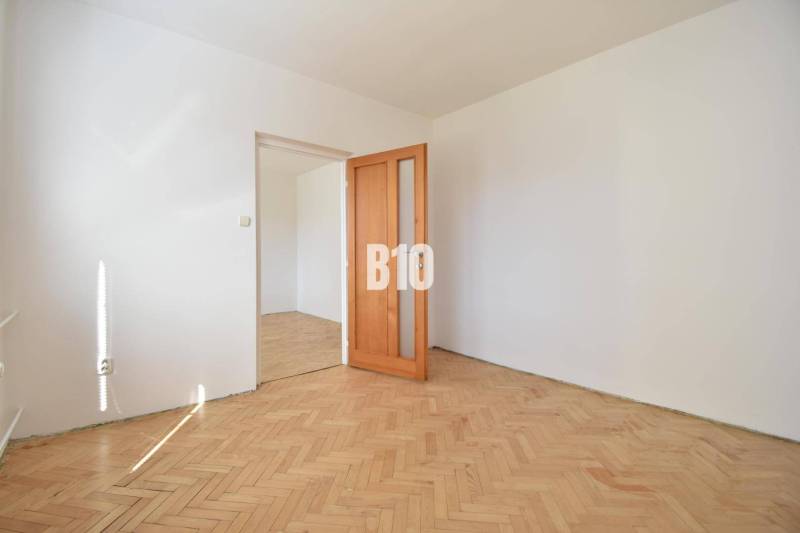 A room in a 4-room apartment with a parquet floor and wooden doors.