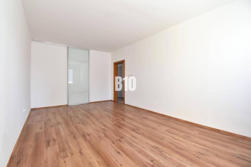 A spacious room with laminate flooring and sliding doors in a 4-room apartment.