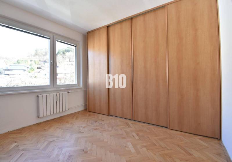 A room in a 4-room apartment with a wooden floor, built-in wardrobe, and a view of the exterior.