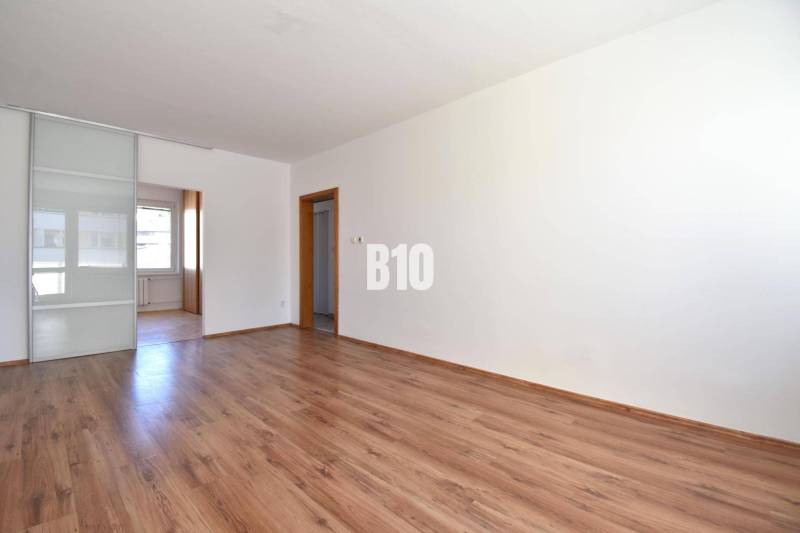 A spacious room with wooden flooring and sliding doors in a 4-room apartment.