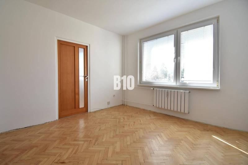 A room in a 4-room apartment with parquet flooring and a large window.