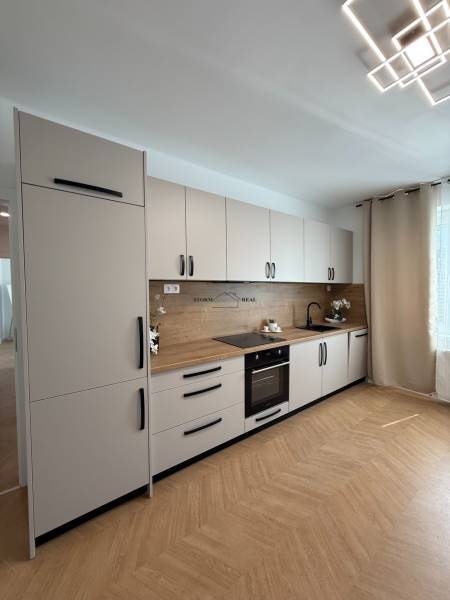 A kitchen in a 3-room apartment with white cabinets and an angled lighting setup.