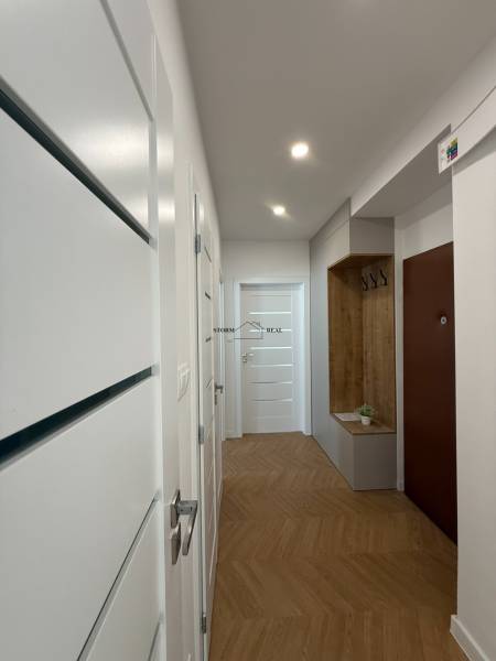 A hallway in a 3-room apartment with white doors and a wooden floor.