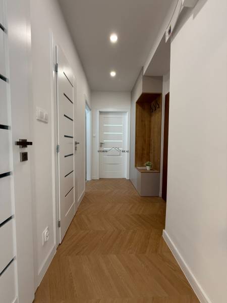 A hallway with a wooden floor in a 3-room apartment with white doors and storage space.