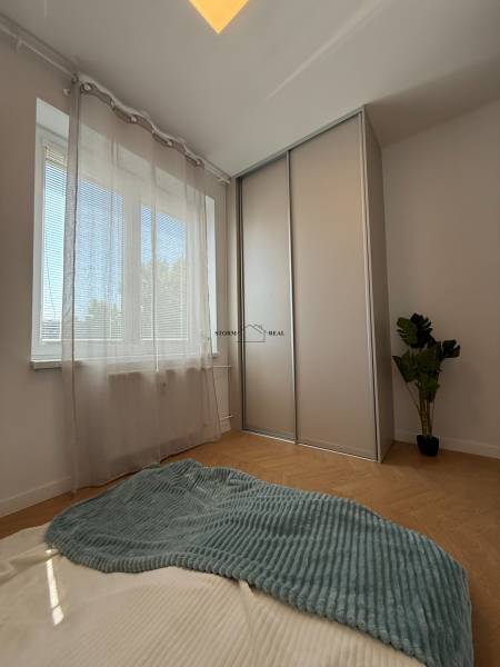 A bright bedroom with a window, a built-in wardrobe, and a plant in a 3-room apartment.