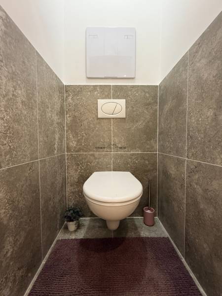 Bathroom with a concealed cistern toilet and gray ceramic tiles in a 3-room apartment.