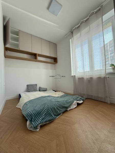Bright bedroom in a 3-room apartment with a low bed and storage cabinets.