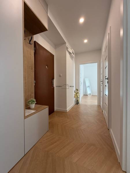 A hallway in a 3-room apartment with a wooden floor and a built-in wardrobe.