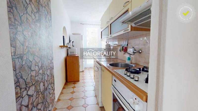 A narrow kitchen in a 3-room apartment with stone cladding and a stove.