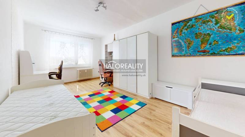 Children's room in a 3-room apartment with a colorful carpet and a desk.