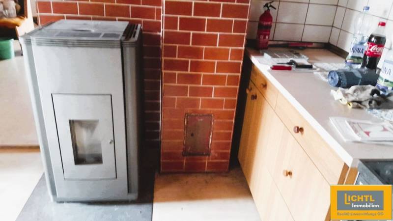 A family house with a brick fireplace, a stove, and a kitchen unit in wooden design.