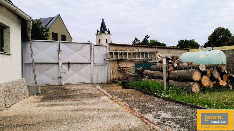 The entrance courtyard of a family house at 2473 Potzneusiedl with a gate and stacked wood.