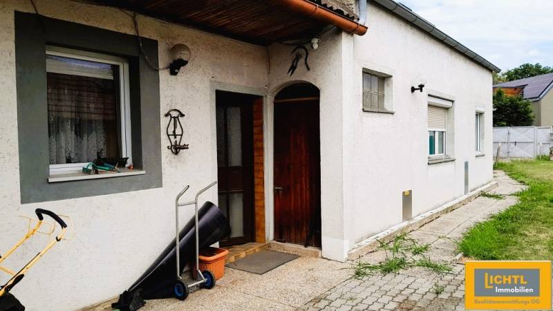 A family house in 2473 Potzneusiedl with a white facade and wooden entrance door.