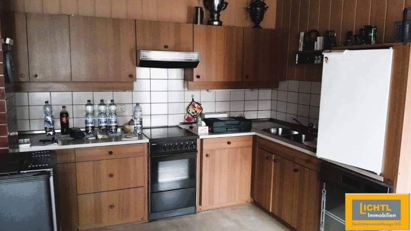 A kitchen in a family house with wooden cabinets and white tiles.