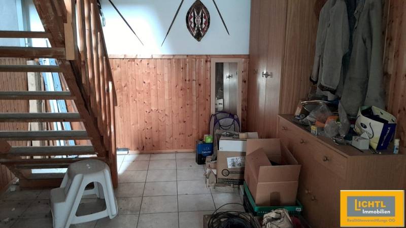Wooden staircase and storage space in a family house with boxes and coats.