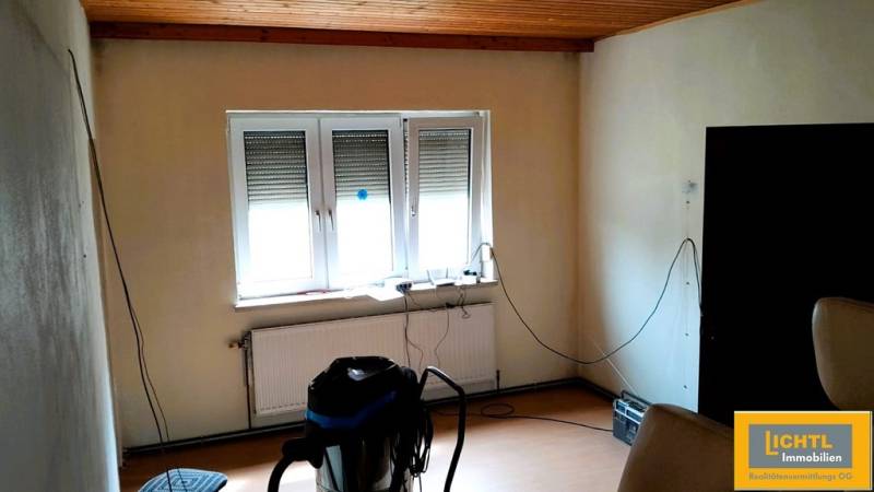 A room in a family house with a window, a radiator, and a wooden ceiling.