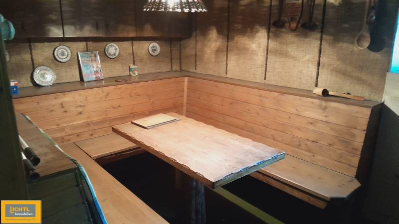 Wooden benches and a table in the corner of a family home's interior with decorative plates on the wall.