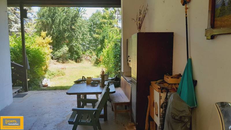 A space in a family house with a view of the garden. A table surrounded by greenery.
