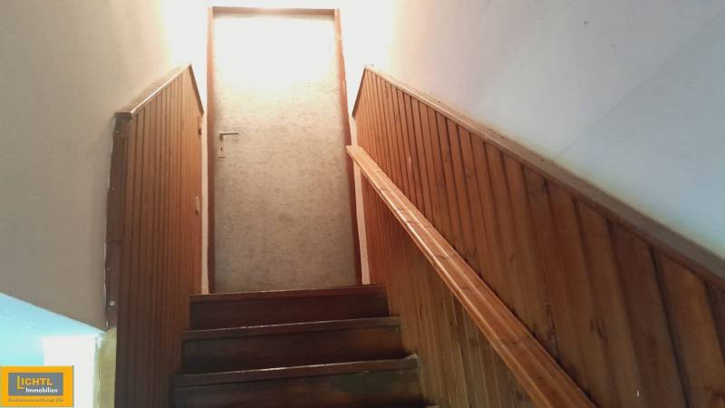 Wooden stairs lead to the door in a family house, lined with wooden paneling.
