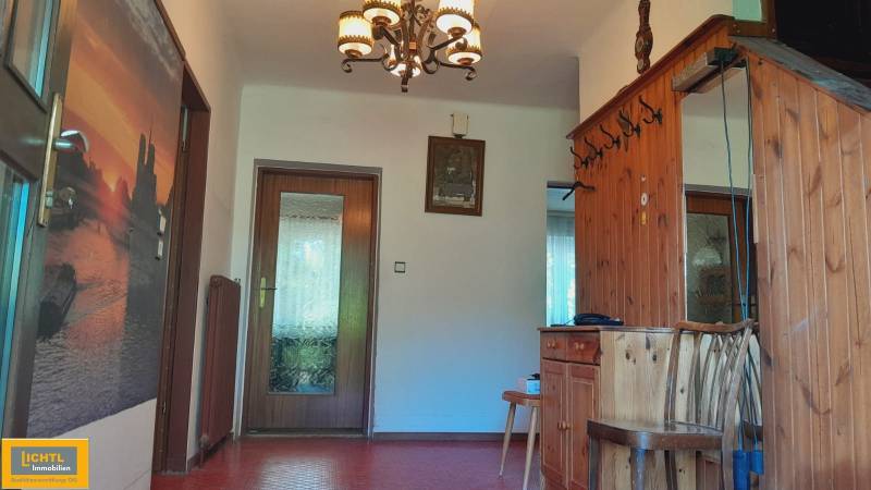 A hallway in a family house with wooden paneling, a mirror, and a decorative chandelier.