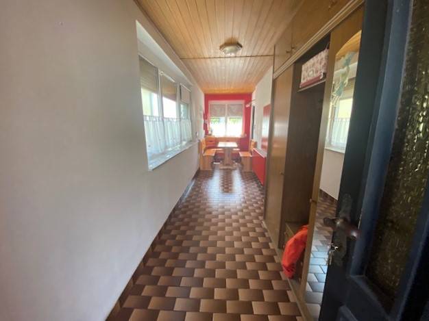 A long hallway in a family house with a patterned floor and a wooden ceiling.