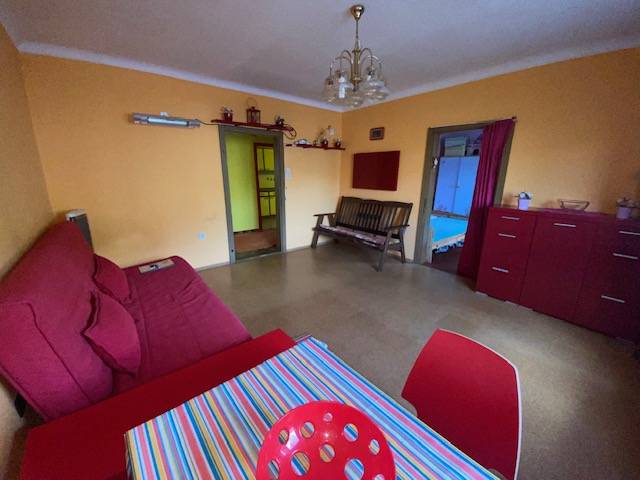 A living room in a family house with red furniture and a colorful table.
