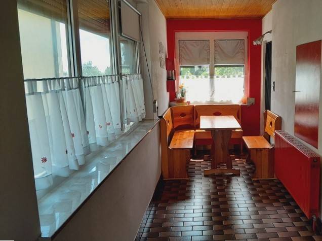 A family house with a wooden seating area in the kitchen, red walls, and a tiled floor.