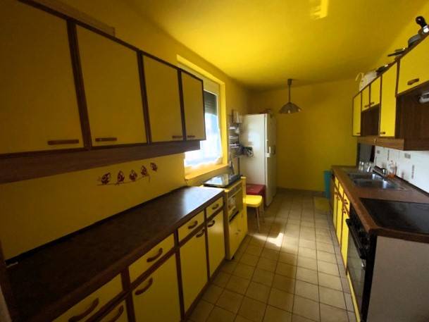 A kitchen in a family house with yellow walls and cabinets, the space is bright and functional.