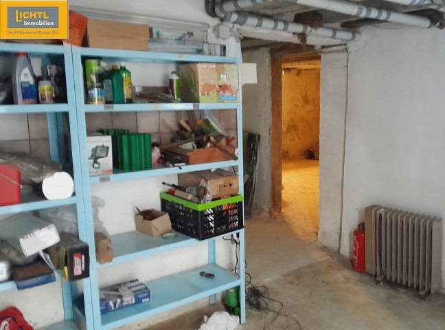 The basement of a family house with a shelf full of tools and pipes on the wall.