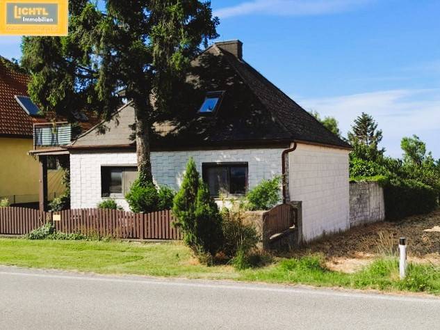 A family house in Hundsheim with a white facade, wooden fence, and surrounding greenery.