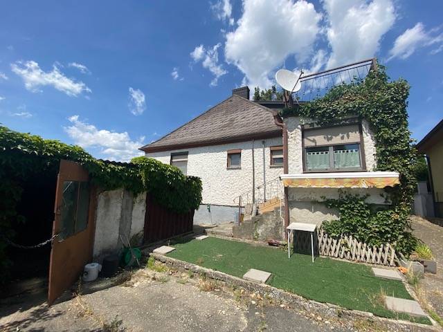 A family house in Hundsheim with a white facade, a terrace, and a garden area.