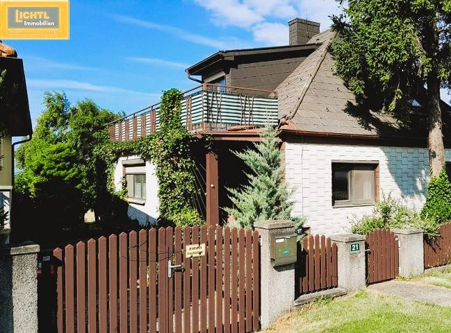 A family house in Hundsheim with a wooden fence, terrace, and abundant greenery.