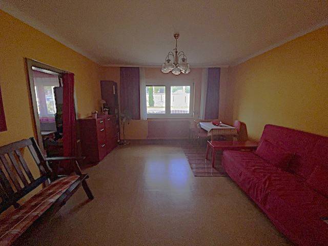 Living room in a family house with colorful walls, a sofa, and a window with a view.