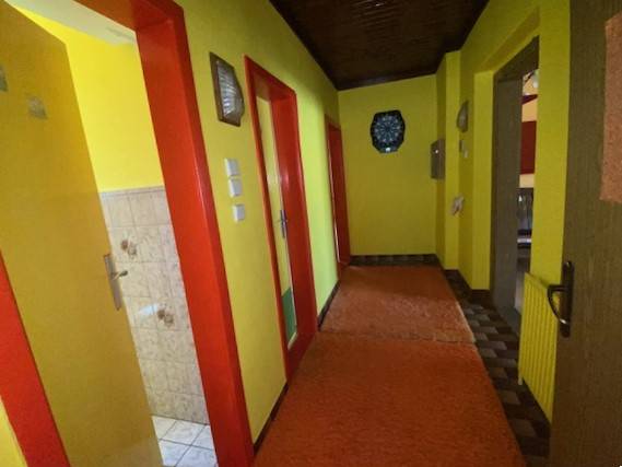 A hallway in a family house with bright yellow walls and red doors.